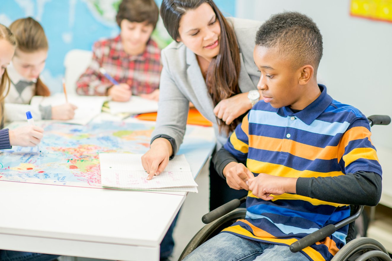 Teacher Helping a Disabled Student with an Assignment